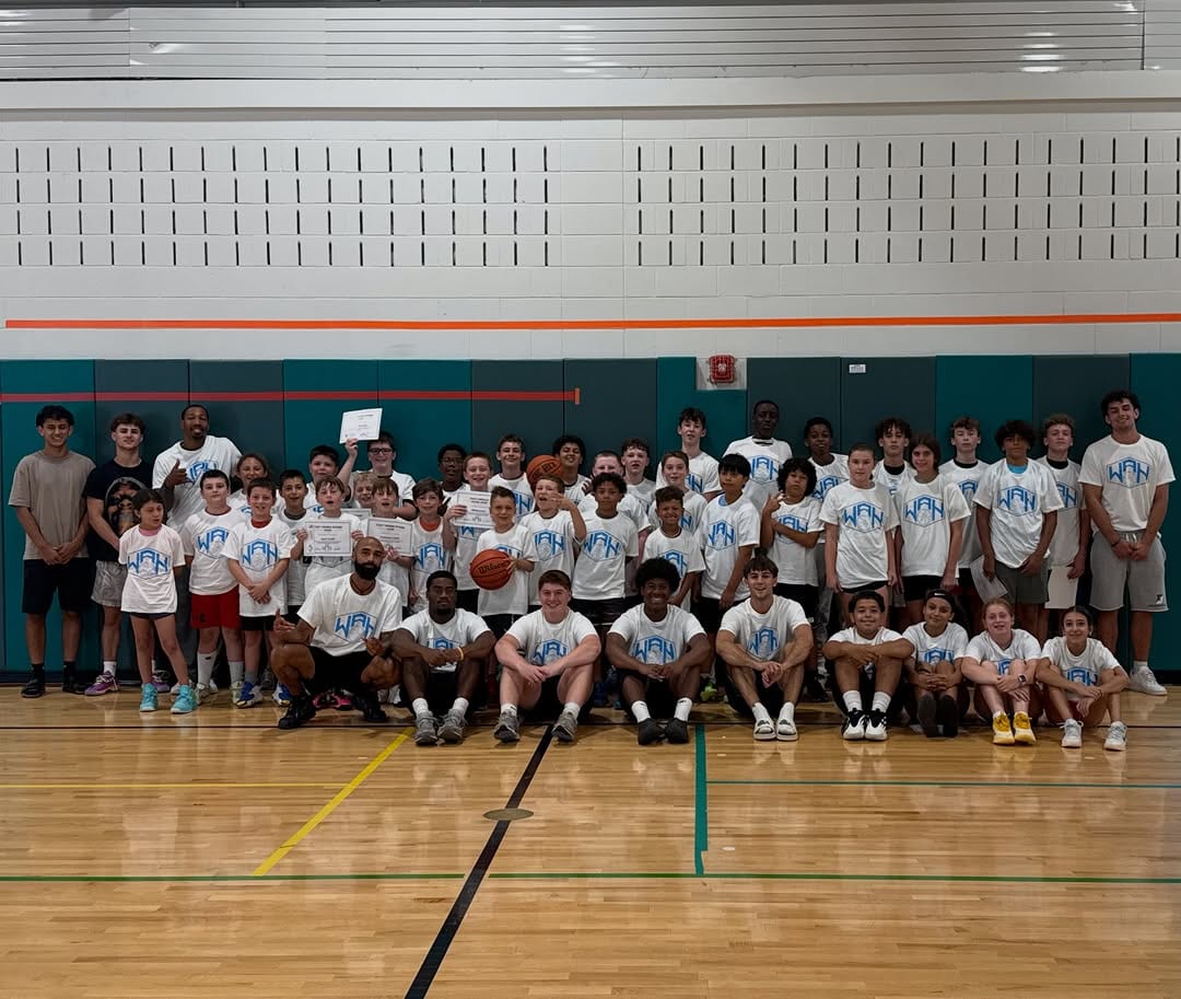 Large group of young players in We All Hoop shirts together in the gym